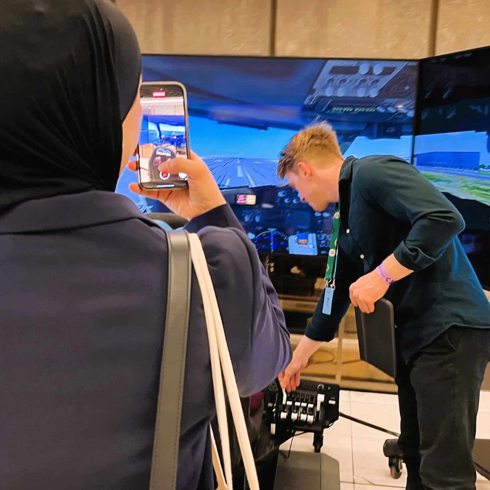 Lady takes a picture of a flight simulator.
